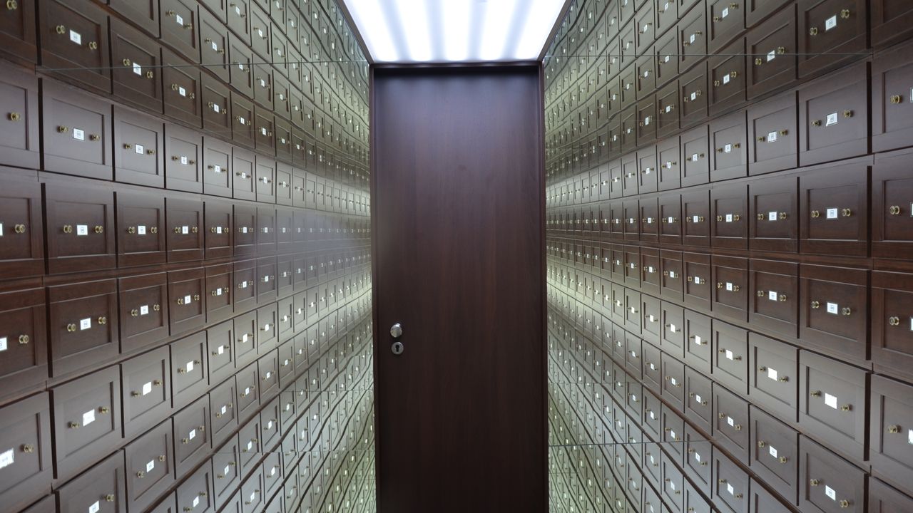 Vault lined with rows of locked safe deposit boxes, illustrating separate encrypted secrets per workspace with SOPS and age
